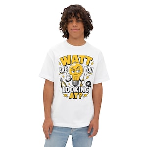 Puede incluir: Una camiseta blanca con un gráfico de una bombilla de dibujos animados con cara, señalando con el dedo y sosteniendo un destornillador. El texto dice WATT ARE YOU LOOKING AT? rodeado de ilustraciones de alicates, cinta aislante y rayos amarillos.