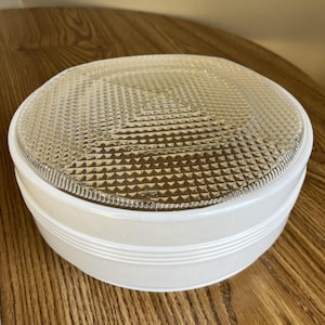 May include: A round ceiling light fixture featuring a smooth, opaque white glass base with three horizontal ridges and a clear, textured glass lens top with a repeating geometric pyramid pattern across the entire surface.