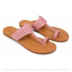 May include: A pair of pink sandals featuring a wide strap with decorative stitching and a scalloped edge, connected to a toe loop. The sandals have a tan footbed with a stitched border detail along the perimeter and a flat sole construction.