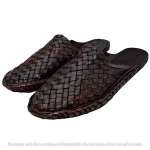 May include: A pair of dark brown slip-on mules featuring a woven leather upper with a crisscross pattern. The footwear has a rounded toe, an open back, and a braided trim detail along the edge of the sole, providing a textured and uniform appearance.
