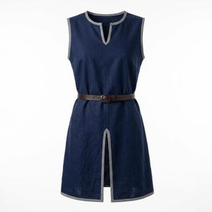 May include: A sleeveless navy blue tunic dress featuring a notched neckline and a front slit at the hem. The edges of the neckline, armholes, and hem are trimmed with a small black and white checkered pattern. A thin brown leather belt is cinched at the waist.