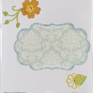 May include: A Sizzix Thinlits set labeled 658956 containing 6 dies for a fancy label and flowers. The packaging displays a light blue damask patterned label shape, an orange flower with green stems, and a yellow flower with a green leaf.