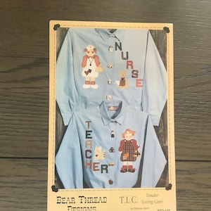 May include: A printed pattern for a cross-stitch embroidery project. The pattern features two images of women dressed as a nurse and a teacher. The text "NURSE" and "TEACHER" is stitched on the shirts of the women. The text "Bear Thread Designs" and "T.L.C. Tender Loving Care by Dianna Akers BTD-137" is printed on the bottom of the pattern.