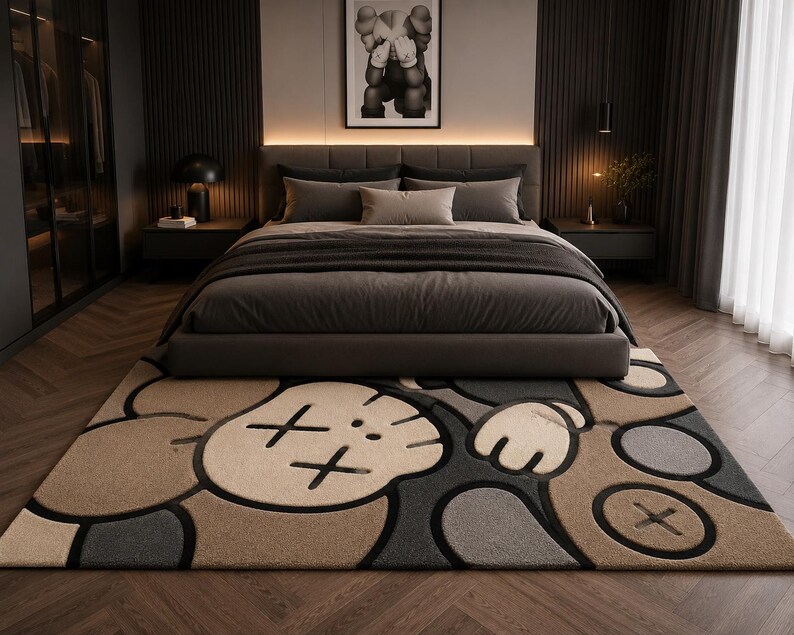May include: A rectangular area rug featuring a large, stylized cartoon character face with X-shaped eyes and gloved hands. The design uses a muted color palette of beige, dark gray, and black, with thick black outlines defining the graphic shapes.