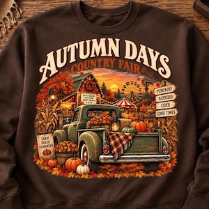 May include: A dark brown sweatshirt featuring a graphic print of a vintage truck filled with pumpkins at a country fair. The text reads AUTUMN DAYS, COUNTRY FAIR, PUMPKINS, HAYRIDES, CIDER, GOOD TIMES, FARM FRESH PUMPKINS, and LOCAL MARKET.
