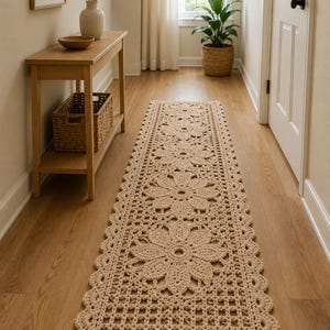Puede incluir: Una alfombra de pasillo rectangular y larga de ganchillo en color beige, con un patrón floral repetitivo de grandes motivos de flores circulares conectados por una estructura de rejilla y rematada con un borde festoneado a lo largo de todo el tejido.