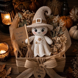 May include: A crocheted ghost doll wearing a beige witch hat with a buckle, holding a small broom, and placed in a gift box with dried flowers. A card reads Boo-tiful Wishes Just for you, and a tag on the burlap bow says Happy Halloween.