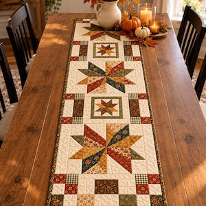 May include: A rectangular quilted table runner featuring a repeating pattern of eight-pointed stars and geometric squares in autumn colors including rust orange, mustard yellow, forest green, and cream with floral and gingham fabric prints.