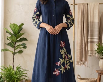 May include: A navy blue knee-length tunic with a mandarin collar, button-down front, and vertical pleats. The sleeves and lower side feature embroidered floral patterns in shades of red, pink, and light green. Paired with matching navy blue trousers.