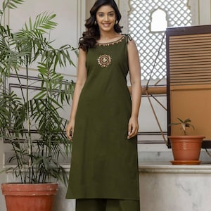 May include: An olive green sleeveless straight-cut kurta with wide-leg trousers. The neckline features a decorative border with small metallic accents, and a circular embroidered motif with gold-toned details is centred on the chest area.