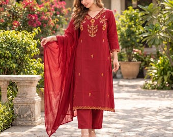May include: A deep red three-piece outfit consisting of a long-sleeved kurta with a V-neckline, matching straight-leg trousers, and a lightweight dupatta. The kurta features intricate gold and orange floral embroidery around the neckline.