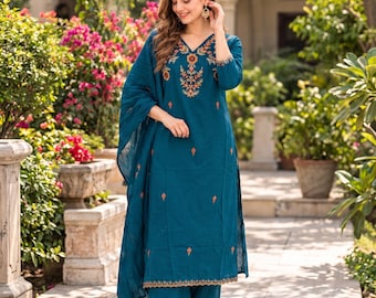 May include: A teal blue three-piece outfit consisting of a long-sleeved straight-cut tunic with a V-neckline, wide-leg trousers, and a matching lightweight dupatta. The tunic features intricate floral embroidery in orange, green, and gold.