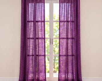 May include: A pair of floor-length, semi-sheer purple curtains with a subtle, crinkled texture. The curtains are hung on a white rod and feature a pleated top header, allowing light to filter through the fabric onto the window panes.