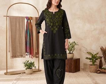 May include: A black long-sleeved tunic featuring olive green embroidery around the neckline, sleeves, and hem, paired with matching black loose-fitting trousers that display an olive green heart-shaped embroidery on the lower leg area.