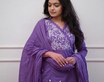 May include: A vibrant purple kurta set featuring a V-neckline with intricate white floral embroidery. The garment includes a matching solid purple dupatta with a textured, crinkled finish and small white floral accents on the main tunic piece.