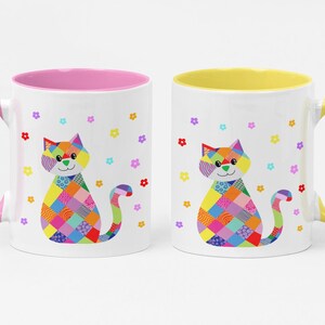 May include: Two white ceramic mugs featuring a colourful patchwork cat illustration with various geometric patterns. One mug has a pink handle and interior, while the other has a yellow handle and interior. Small multi-coloured flowers surround the cat.