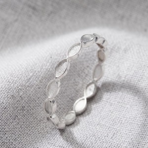 May include: A silver-toned ring featuring a continuous band of repeating marquise-shaped links. Each individual link has a textured, matte-finished center surrounded by a smooth, polished metal border, creating a delicate and uniform circular design.