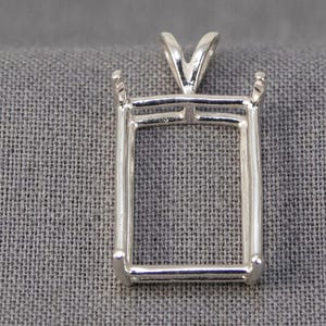 May include: A silver-toned rectangular pendant setting featuring four prongs at the corners to secure a gemstone. The metal frame has a polished finish and includes a triangular bail at the top for attaching to a chain or necklace cord.