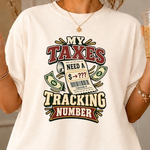 May include: An ivory t-shirt featuring a graphic print with the text "MY TAXES NEED A TRACKING NUMBER" and an illustration of a receipt showing "$ -> ???" with a barcode. The design includes green dollar bill icons and red accents.