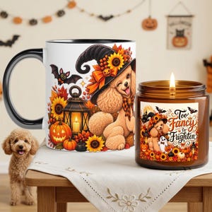 May include: A white ceramic mug with a black handle and a brown glass candle jar, both featuring a graphic of a poodle wearing a witch hat, sunflowers, pumpkins, and a lantern. The candle label includes the text Too Fancy to Frighten.