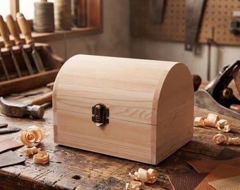 May include: A light-coloured wooden chest with a curved, arched lid and a metal latch closure. The box features a natural wood grain finish and is constructed with a rectangular base and a rounded top, providing a simple, functional storage container.