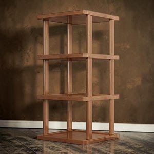 Può includere: Uno scaffale in legno a quattro livelli con una base quadrata e tre ripiani quadrati aggiuntivi sostenuti da quattro montanti verticali. La struttura presenta una finitura in legno color marrone medio con una superficie liscia e lucida.