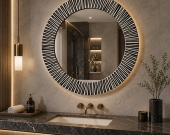 May include: A round wall mirror featuring a wide frame with a black and white striped pattern. The mirror includes integrated backlighting that casts a soft glow around its circular perimeter, reflecting a bathroom interior with marble surfaces.