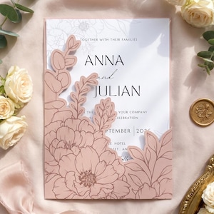 May include: A wedding invitation card featuring a dusty pink laser-cut floral overlay with eucalyptus and peony designs. The white cardstock displays the text Anna and Julian, along with September 2026, in black serif and script typography.