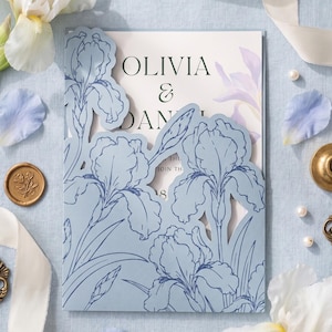 May include: A rectangular wedding invitation card featuring a light blue laser-cut overlay with a detailed iris flower pattern. The white inner card displays the text OLIVIA & DANIEL. The design includes dark blue line art of irises on the cover.