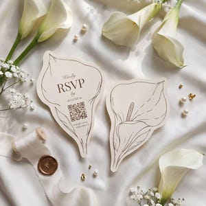Puede incluir: Dos tarjetas troqueladas con forma de calas en papel color crema. Una tarjeta incluye el texto "Kindly RSVP by AUGUST 10" y un c&oacute;digo QR. La otra tarjeta muestra una ilustraci&oacute;n de l&iacute;nea de una cala. Ambas tarjetas tienen detalles en tinta marr&oacute;n.