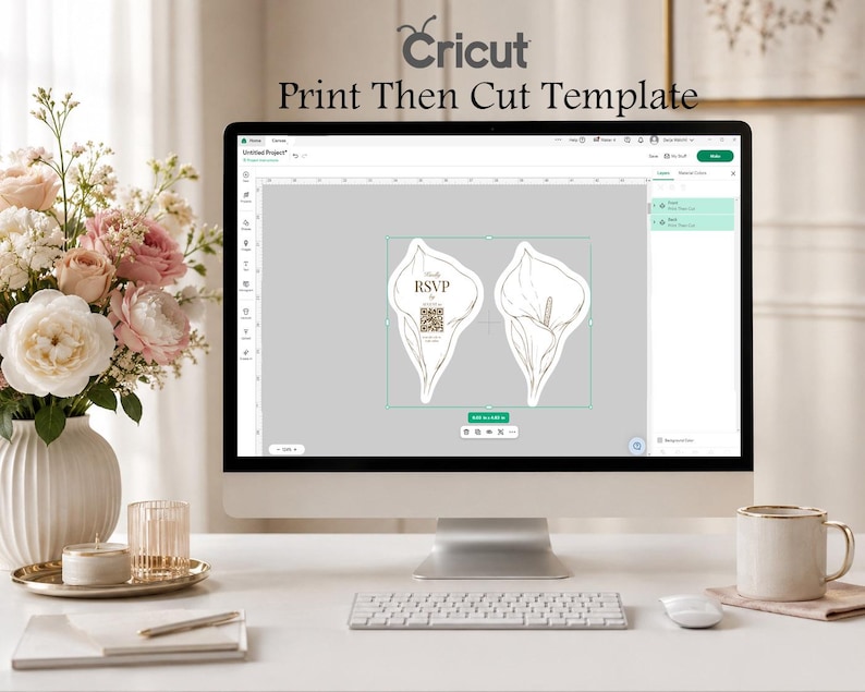 Puede incluir: Un monitor de computadora que muestra la interfaz del software Cricut Print Then Cut Template. La pantalla muestra dos dise&ntilde;os de tarjetas con forma de lirio de cala, uno con el texto RSVP y un c&oacute;digo QR. El monitor est&aacute; sobre un escritorio con teclado.
