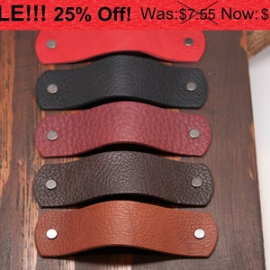 May include: Five leather drawer pulls in different colors, including red, black, burgundy, brown, and orange. The pulls are displayed on a wooden surface. SALE!!! 25% Off! Was: $7.55 Now: $5.66