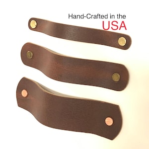 Peut inclure: Trois poignées de tiroir en cuir marron avec des rivets en laiton et en cuivre. Fabriqué à la main aux États-Unis.