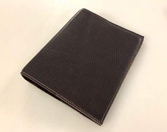 Op de afbeelding: Een donkerbruin lederen notitieboek met een gestikte rand.
