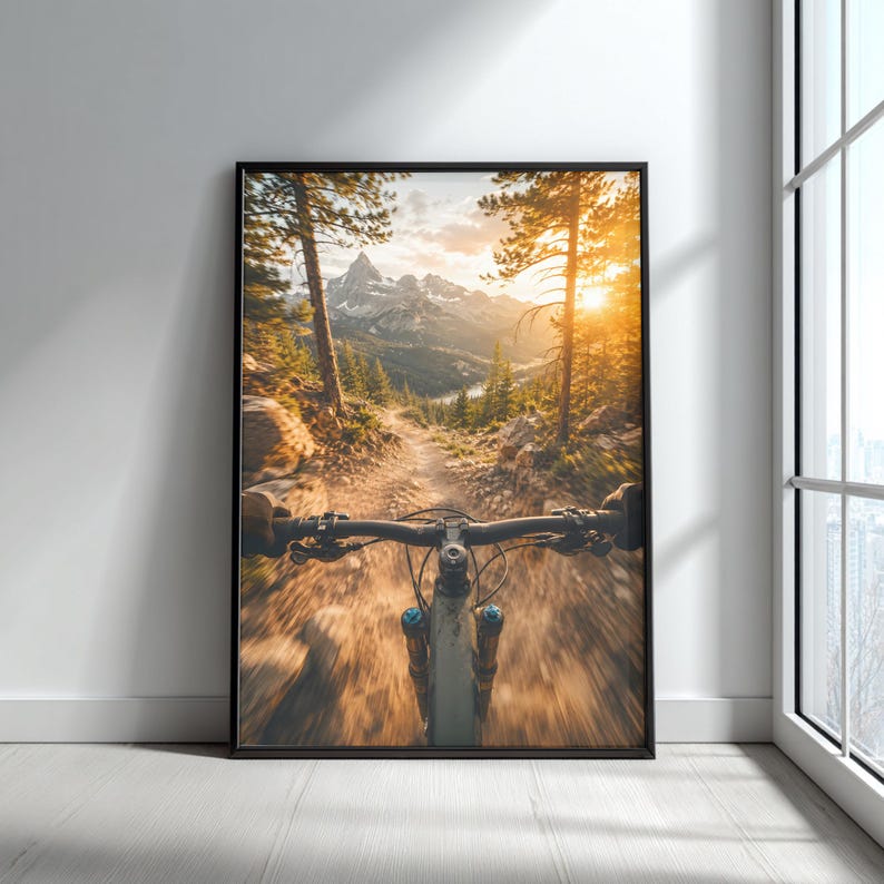 K&ouml;nnte beinhalten: Ein gerahmter Wandkunstdruck mit einer Ego-Perspektive eines Mountainbikes, das einen staubigen Feldweg hinunterf&auml;hrt. Die Szene zeigt eine sonnenbeschienene Bergkette im Hintergrund mit hohen Kiefern und einem hellen, goldenen Sonnenuntergang.
