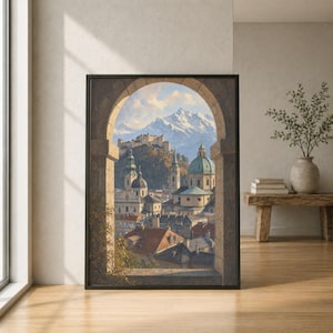 May include: A framed wall art print depicting a view through a stone archway of a European city with terracotta rooftops, church domes, and a hilltop fortress, all set against a backdrop of snow-capped mountains under a soft blue sky.