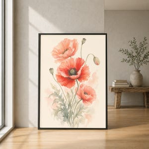 Op de afbeelding: Een ingelijste verticale wandkunstprint met een aquarelillustratie van drie levendige rode klaprozen met groene stelen en bladeren op een crèmekleurige achtergrond. Het kunstwerk toont zachte penseelstreken en florale details.