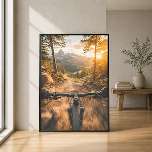 K&ouml;nnte beinhalten: Ein gerahmter Kunstdruck mit einer Ich-Perspektive beim Mountainbiken auf einem Waldweg. Die Szene zeigt einen hellen Sonnenuntergang &uuml;ber fernen schneebedeckten Bergen, umgeben von hohen Kiefern und einem dynamischen Bewegungseffekt.
