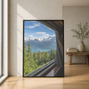 Può includere: Una stampa artistica da parete incorniciata che mostra una vista dal finestrino di un treno su un paesaggio di fitti pini verdi, un lago turchese e cime montuose innevate sotto un cielo azzurro con nuvole e una tenda trasparente.