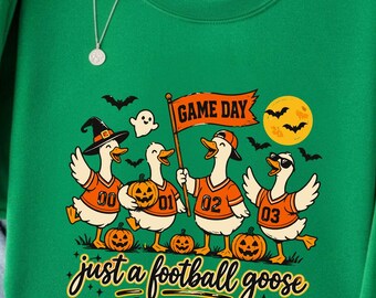 May include: A bright green crewneck sweatshirt featuring a graphic of four geese wearing orange football jerseys and hats, with pumpkins, bats, a full moon, and the text "GAME DAY" and "just a football goose" printed in black and orange ink.