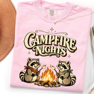 Retro illustration of two raccoons wearing bandanas roasting marshmallows over a campfire with the text Campfire Nights above them on a cream background. — product photo 15