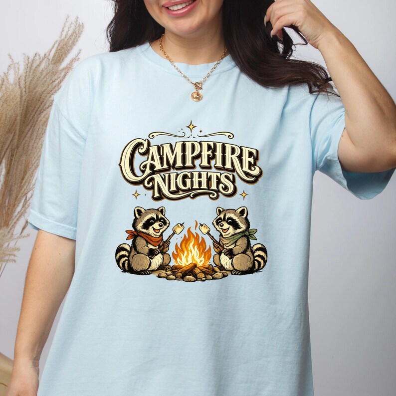 Retro illustration of two raccoons wearing bandanas roasting marshmallows over a campfire with the text Campfire Nights above them on a cream background. — product photo 8