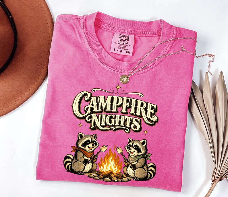 Retro illustration of two raccoons wearing bandanas roasting marshmallows over a campfire with the text Campfire Nights above them on a cream background. — product photo 5