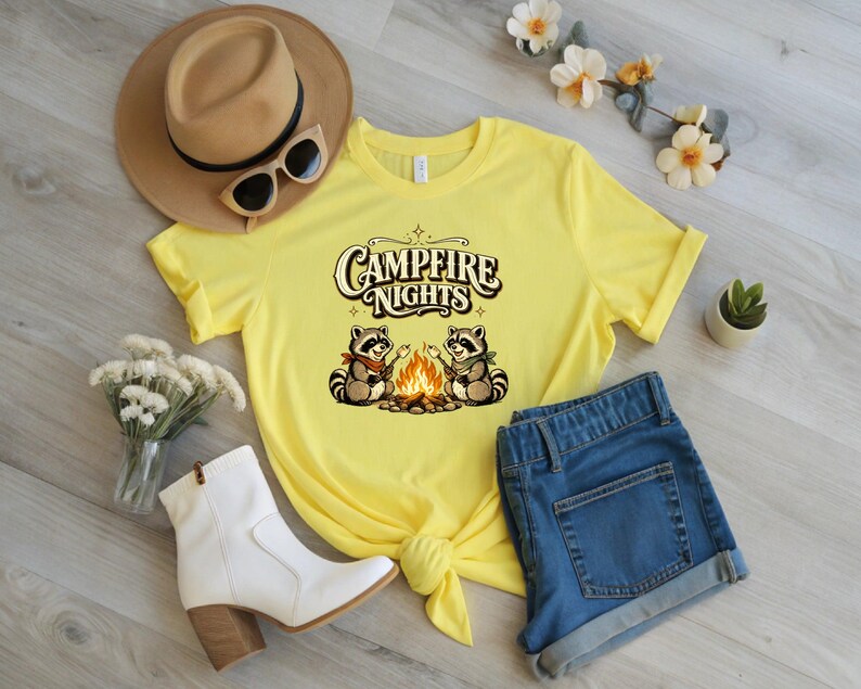 Retro illustration of two raccoons wearing bandanas roasting marshmallows over a campfire with the text Campfire Nights above them on a cream background. — product photo 2