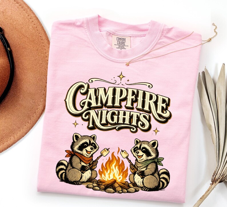 Retro illustration of two raccoons wearing bandanas roasting marshmallows over a campfire with the text Campfire Nights above them on a cream background. — product photo 15