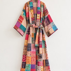 May include: A long-length robe featuring a patchwork design composed of various rectangular fabric segments in vibrant shades of pink, orange, teal, yellow, and purple, finished with a matching tie belt and wide sleeves.