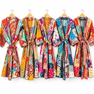 May include: Five long-sleeved robes hanging on wooden hangers, each featuring a vibrant patchwork design composed of various colorful floral and geometric fabric patterns, with a matching tie belt at the waist for each garment.