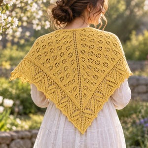 Könnte beinhalten: Ein dreieckiges senfgelbes Tuch mit einem komplexen Strickspitzenmuster, einem Mittelsteg und einem dekorativen blattartigen Rand. Das Tuch liegt über den Schultern und zeigt die detaillierte, durchbrochene Textur und die leuchtende Farbe.