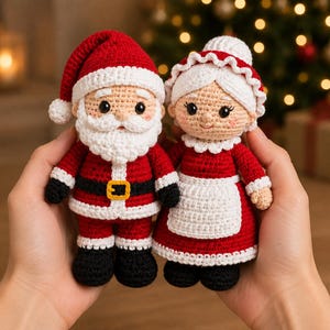 Könnte beinhalten: Zwei Amigurumi-Häkelpuppen, die den Weihnachtsmann und Frau Weihnachtsmann darstellen. Der Weihnachtsmann trägt einen roten Anzug mit weißem Besatz, einen schwarzen Gürtel mit gelber Schnalle und schwarze Stiefel. Frau Weihnachtsmann trägt ein rotes Kleid mit weißer Schürze, Kragen und Haube.