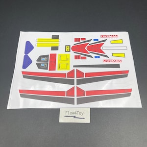 May include: A rectangular sheet of adhesive decals featuring various geometric shapes in red, yellow, blue, and black. The stickers include two long red and black wing-like strips, smaller rectangular accents, and two labels with the text LIVEMAN.